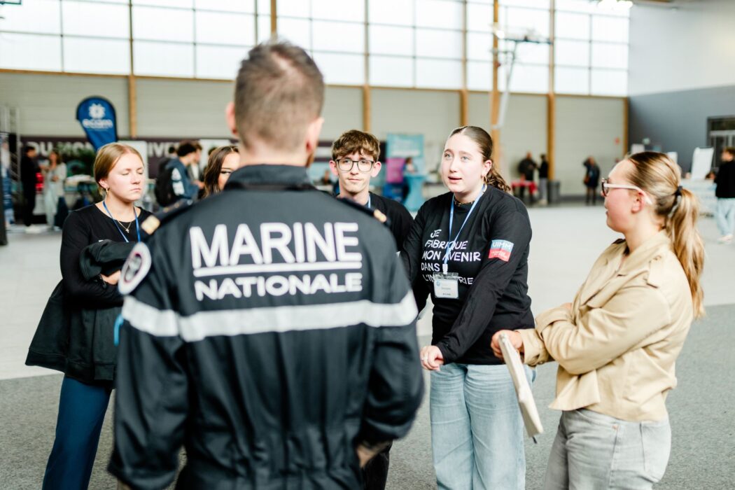 Échange entre un marin de la Marine Nationale et des étudiants devant les stands partenaires