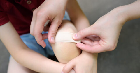 Enfant blessé après une chute, auquel on applique un pansement.